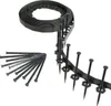 A roll of black flexible garden edging and a pile of black stakes on a white background. Produktbild-Vorschau