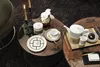 A tea set and plate are arranged on two round coffee tables, with candles and flowers as decoration. Náhled obrázku produktu
