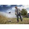 A man is using a string trimmer in a grassy area with a building in the background. Voir les images du produit