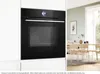 A modern kitchen scene featuring a built-in oven and a dining area. Produktbild-Vorschau