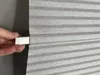 A hand is holding a small silver object against a pleated gray fabric. Produktbild-Vorschau