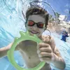 A young boy is underwater in a swimming pool, smiling and holding a green ring. Anteprima dell’immagine prodotto