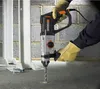 A person wearing gloves is using a WORX WX339 Bohrhammer to drill a hole in a concrete floor. Náhled obrázku produktu