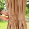 A close-up of a tan-colored outdoor curtain being held by a person's hands. Produktbild-Vorschau