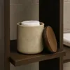 A beige polyresin cotton pad holder with a wooden lid sits on a dark wooden shelf. Anteprima dell’immagine prodotto