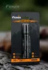 A Fenix E20 V2.0 flashlight in its retail packaging, set against a blurred natural background. Náhled obrázku produktu