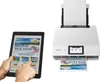 A tablet displaying a beach holiday advertisement is shown next to a white Canon printer that is printing a similar advertisement. Podgląd zdjęcia produktu