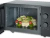A microwave oven with a glass dish of vegetables inside. Produktbild-Vorschau