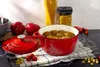 A red Dutch oven filled with meatballs is placed on a checkered cloth on a dark countertop, surrounded by ingredients like bell peppers, cherry tomatoes, and pasta. Anteprima dell’immagine prodotto