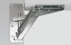 A close-up view of a metal hinge mechanism with a spring, attached to a white surface. Produktbild-Vorschau