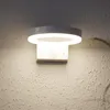 A modern white wall light with a circular LED light fixture mounted on a textured wall. Produktbild-Vorschau