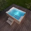 An outdoor whirlpool on a wooden deck, surrounded by grass and trees. Podgląd zdjęcia produktu