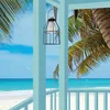 A vintage-style solar lantern hangs on a porch overlooking a tropical beach scene with palm trees. Náhľad obrázku produktu
