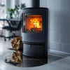 A modern living room with a black wood-burning stove and a stack of firewood. Produktbild-Vorschau