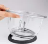 A hand is shown placing the lid on a clear glass bowl with metal blades inside. Produktbild-Vorschau