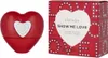 A red heart-shaped perfume bottle and its packaging are displayed side-by-side against a white background. Produktbild-Vorschau