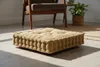 A floor cushion is placed on a wooden floor in a room with a chair and a plant in the background. Podgląd zdjęcia produktu
