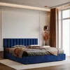 A bedroom scene featuring a dark blue upholstered bed with pillows and a throw blanket. Anteprima dell’immagine prodotto