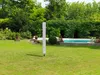 A white cylindrical object stands in a grassy yard next to a swimming pool. Produktbild-Vorschau