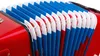 A close-up view of the bellows of a red accordion with blue and white trim. Podgląd zdjęcia produktu