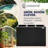 A collage of images showing a swimming pool, a garden path, and an indoor plant, alongside a black polyrattan planter with three inner pots. The text "GRÜN. SCHÖN. CLEVER." and "Präsentiere deine Pflanzen - drinnen & draußen." are displayed. Anteprima dell’immagine prodotto