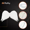 A product image featuring white angel wings and close-ups of feathers and elastic straps, with a brand logo. Produktbild-Vorschau