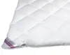 A close-up of a white quilted duvet with a label attached to the corner. Produktbild-Vorschau