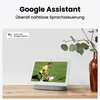 A smart display device is shown on a wooden table, with a vase of greenery in the background. The display shows a child playing with a dog. Produktbild-Vorschau