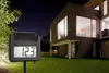 A digital thermometer with a solar panel is placed in a garden in front of a modern house at night. Produktbild-Vorschau