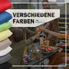 People enjoying an outdoor gathering around a table, with a stack of colorful cushions in the foreground. Produktbild-Vorschau