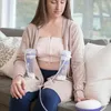 A woman is sitting on a couch using a breast pump. Produktbild-Vorschau