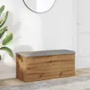 A wooden storage bench with a gray upholstered top is placed in a hallway next to a large potted plant and a mirror on the wall. Produktbild-Vorschau