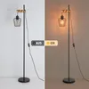 A split image showing a floor lamp in two different lighting conditions: off and on. The left side shows the lamp in a bright, neutral setting, while the right side shows it illuminated in a warm, ambient light. Produktbild-Vorschau
