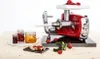 A red and silver meat grinder with jars of jam and a slice of toast with jam on a wooden surface. Anteprima dell’immagine prodotto