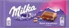 A Milka chocolate bar with colorful candy-coated chocolate pieces, set against a mountainous backdrop. Produktbild-Vorschau