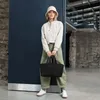 A woman stands in an urban-like setting, holding a black cooler bag. Voir les images du produit