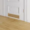 A close-up shot of a wooden ventilation grille installed at the bottom of a white door, with a wooden floor in the foreground. Produktbild-Vorschau