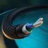 A close-up, cutaway view of a black braided audio cable, showing its internal wires and shielding, against a swirling teal and dark green background. Náhled obrázku produktu
