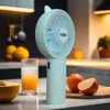 A portable fan and a glass of juice are displayed on a kitchen counter. Produktbild-Vorschau