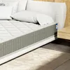 A close-up view of a mattress on a bed frame, with pillows and a bedside table visible. Voir les images du produit