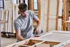 A man is sanding a wooden door frame in a workshop. Anteprima dell’immagine prodotto