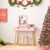 A pink vanity table with a stool and mirror, decorated for Christmas with a tree, wreath, and festive sign. Podgląd zdjęcia produktu