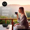 A woman is enjoying tea on a balcony with a scenic mountain view. Produktbild-Vorschau