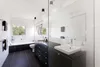 A modern bathroom with a bathtub, toilet, and vanity with a large mirror. Anteprima dell’immagine prodotto