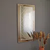 A rectangular mirror with a decorative frame is mounted on a gray wall, with dried plants in a pot in the foreground. Produktbild-Vorschau
