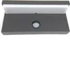 A close-up, straight-on view of a dark gray outdoor wall light with a white diffuser panel at the top and a motion sensor in the center. Anteprima dell’immagine prodotto