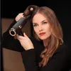 A woman is using a black and gold hair dryer to style her hair. Podgląd zdjęcia produktu