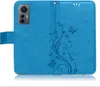 A blue flip case for a smartphone, with a floral and butterfly embossed design. Produktbild-Vorschau