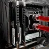 A close-up view of computer components, specifically RAM modules and a liquid cooling system with red coolant. Produktbild-Vorschau