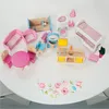 A collection of miniature wooden dollhouse furniture is arranged on a white surface with a floral watercolor design. Voir les images du produit